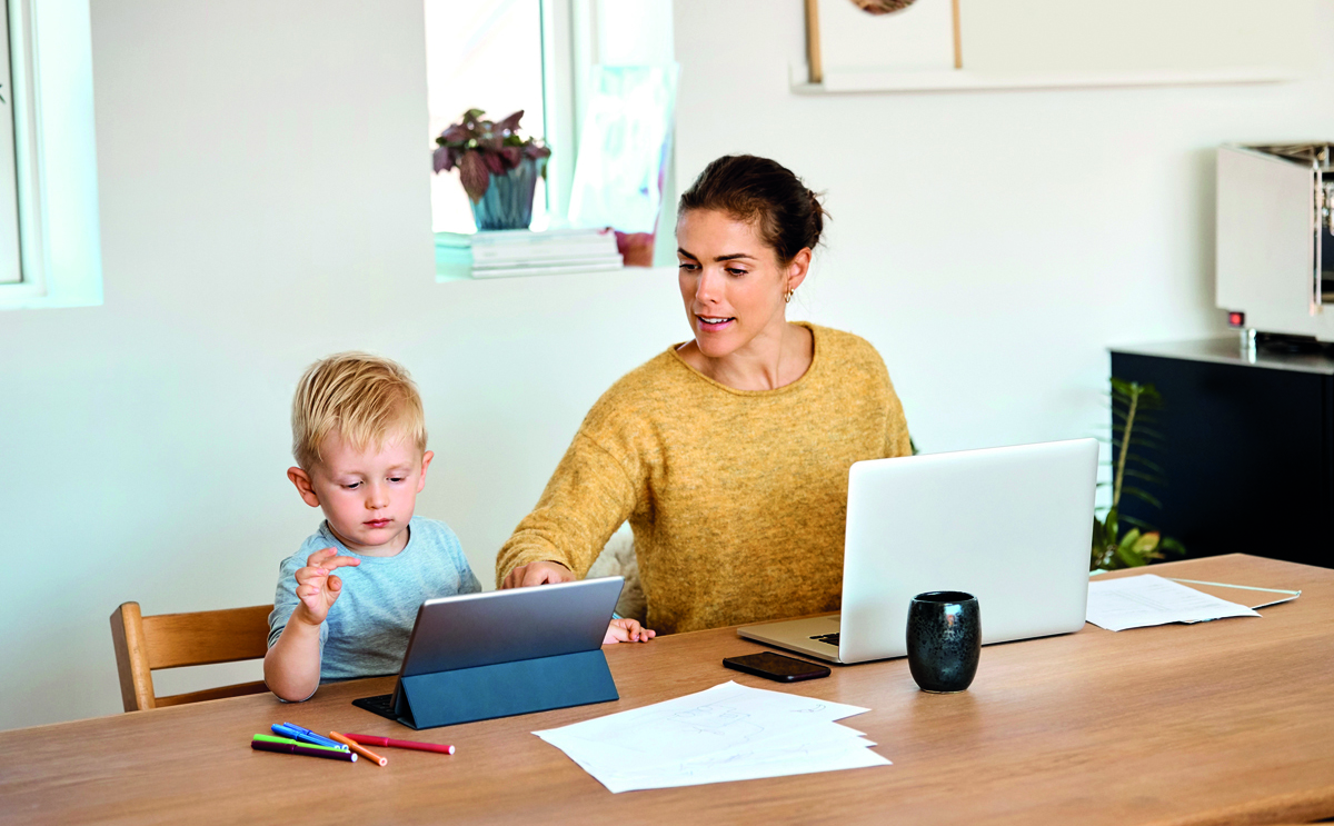Mother assisting son in using tablet PC at table
