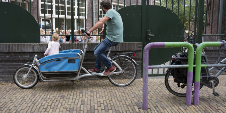 delft, netherlands, 30 june 2017: father waits with cargo bike at kindergarten in dutch town of delft